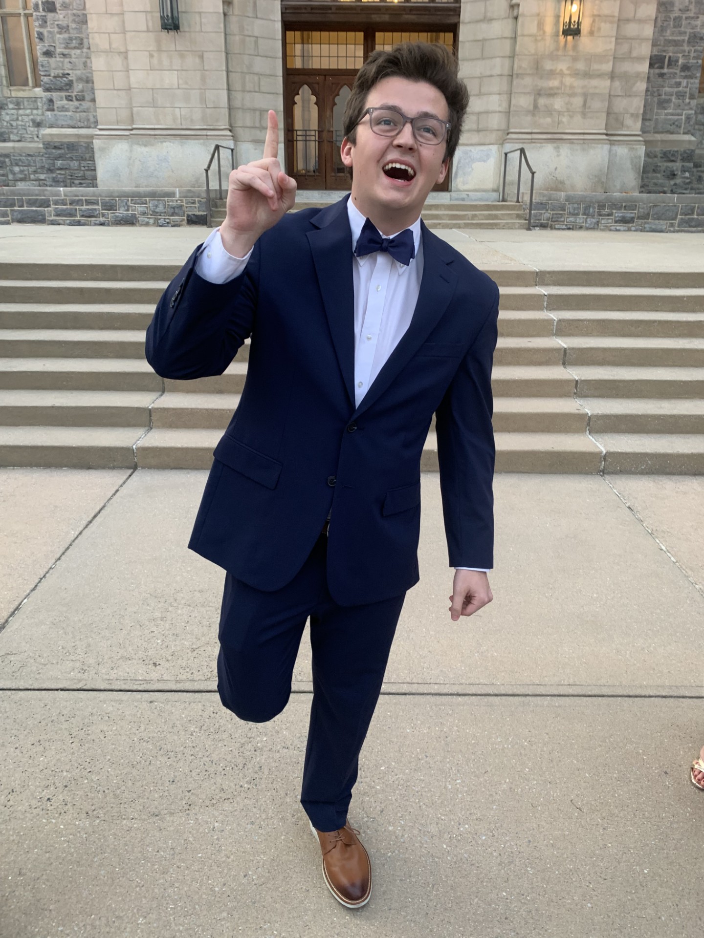 Charlie Steinman celebrating in a suit outside a Gothic university hall