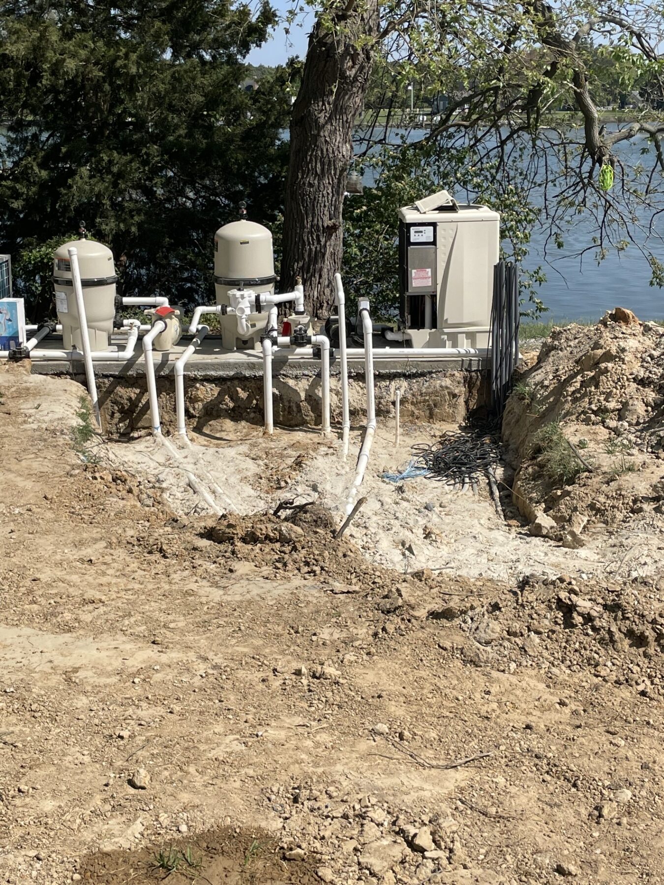 Pool equipment and piping exposed next to the water, before the fence